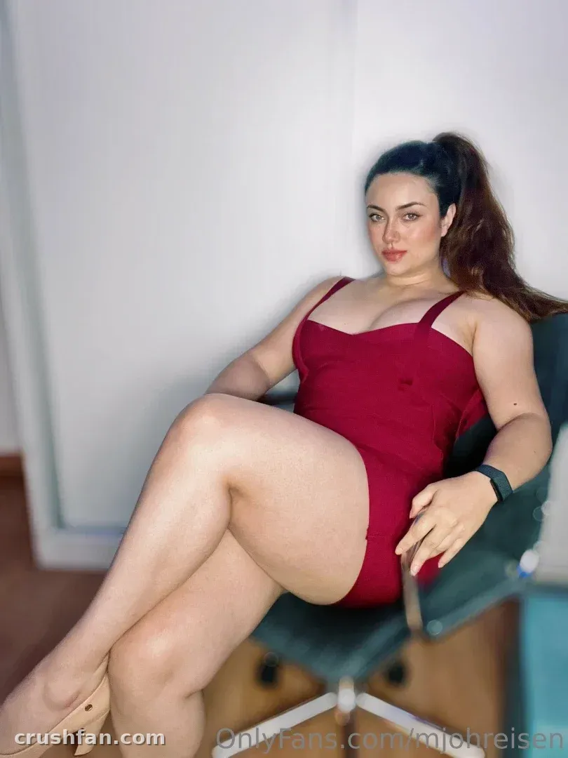 MJ! in a red bodysuit seated on a dark chair indoors