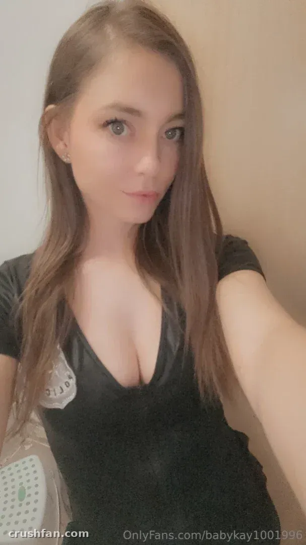 Babykay prenant un selfie en gros plan à l'intérieur dans un haut noir à décolleté profond