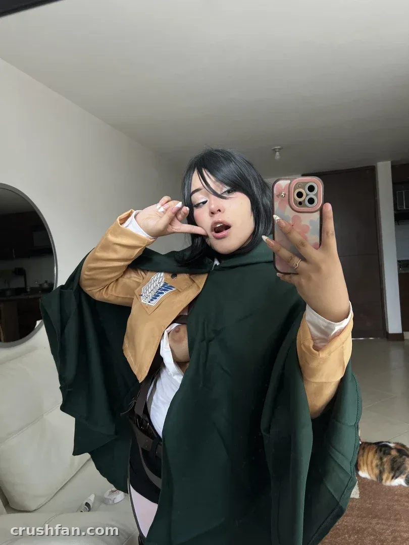 Ana ✧ in a yellow jacket and green cape taking a mirror selfie indoors