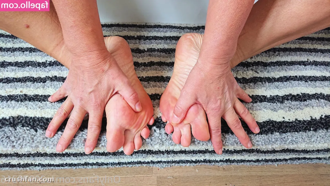 Close-up of hands resting over bare feet on a grey and white striped rug