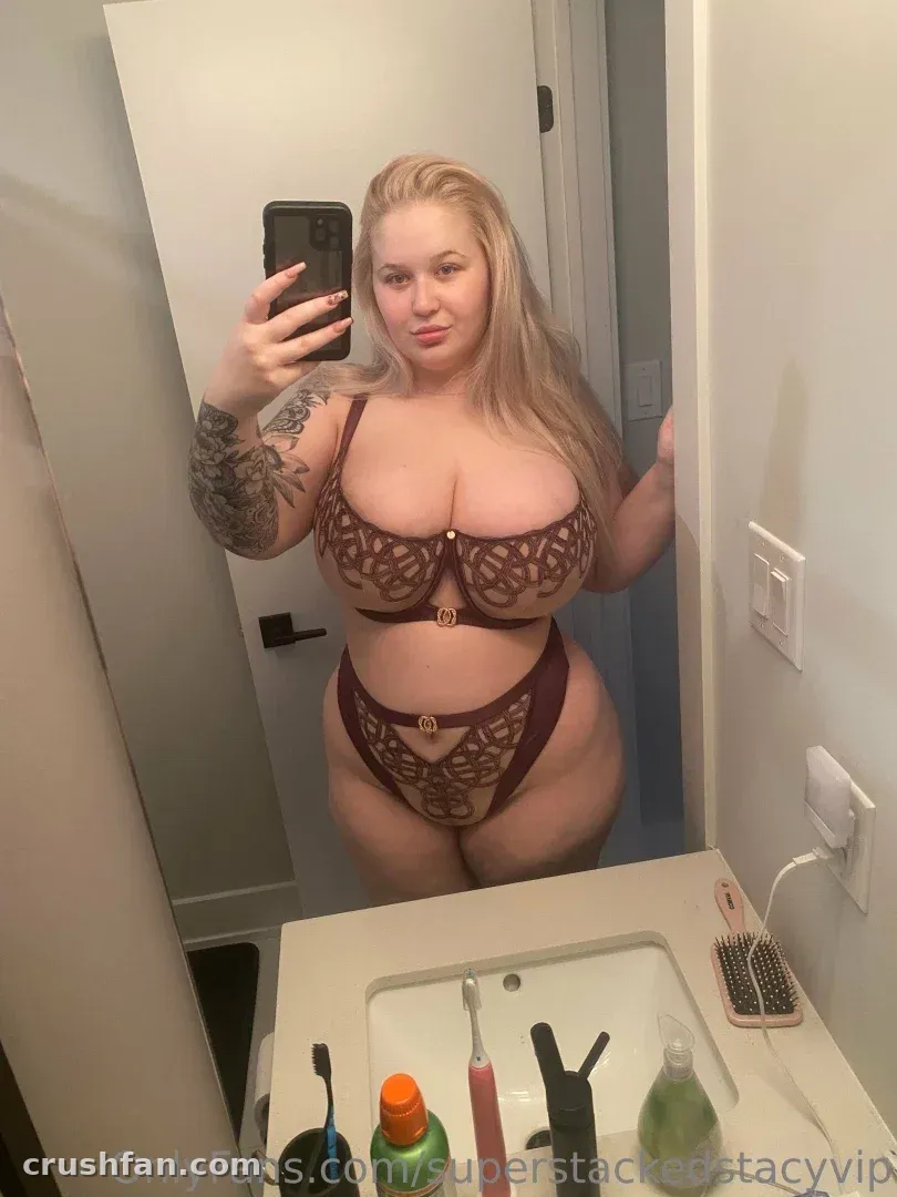 Stacy in burgundy lace lingerie taking a mirror selfie in a bathroom