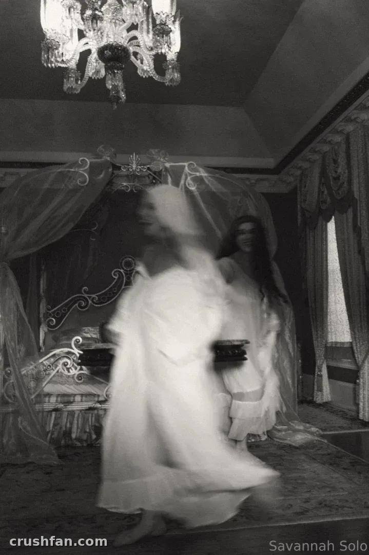 Photo en noir et blanc de Savannah Solo en robe blanche et voile dans une pièce ornée.