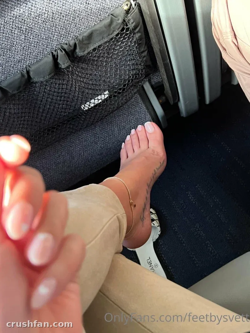Pied nu posé sur un siège de train avec un pantalon beige et une chaîne de cheville dorée.
