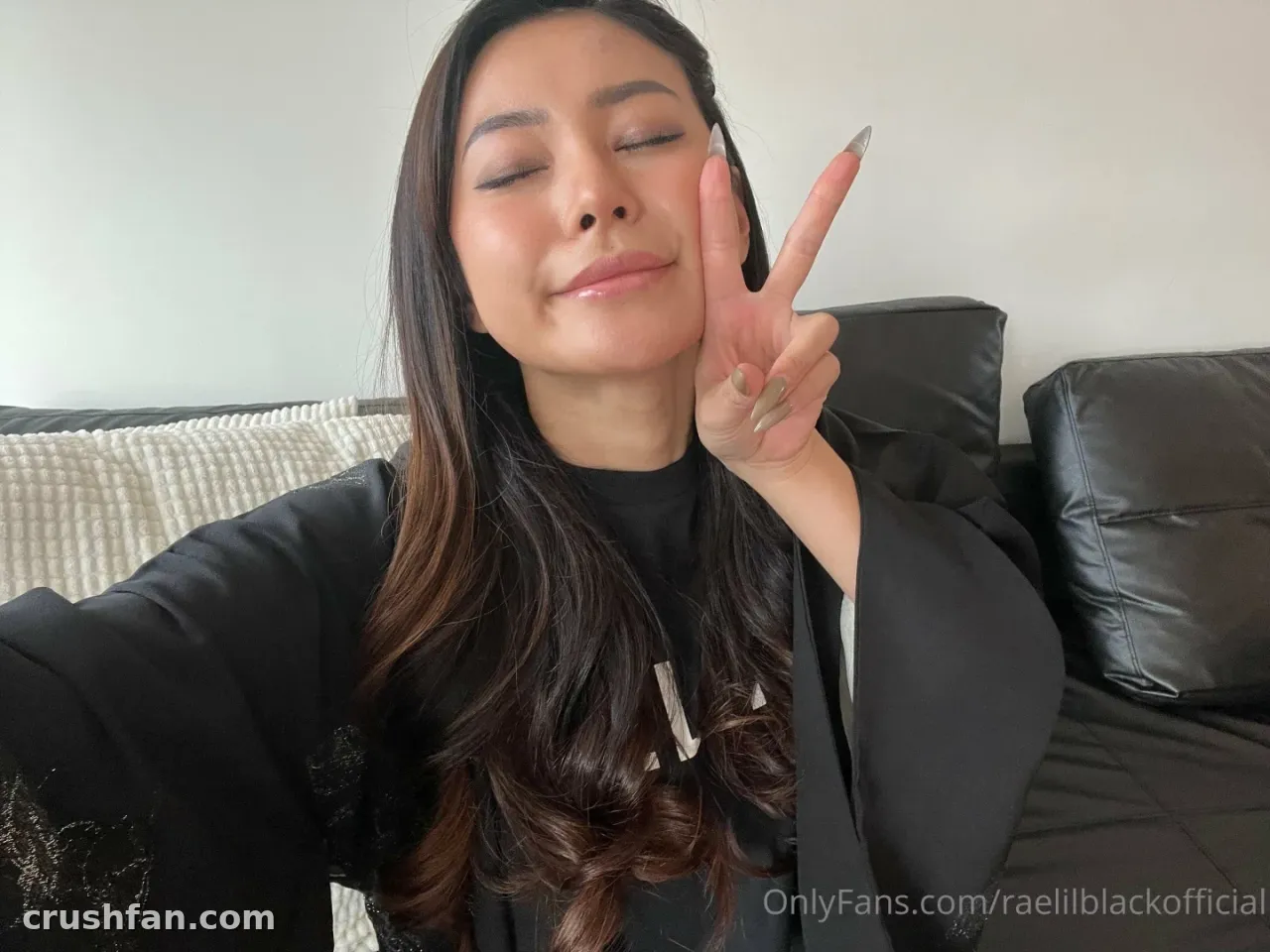 Creator in a black top making a peace sign indoors near a sofa.