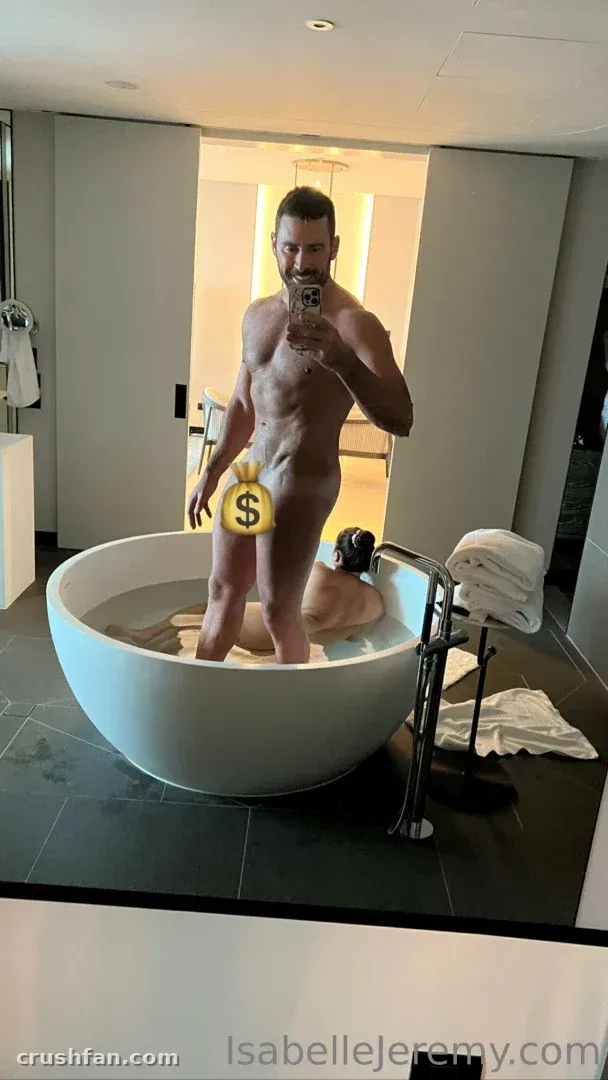 Creator standing in a round bathtub taking a mirror selfie in a bright modern bathroom