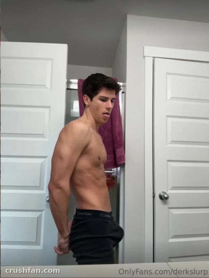 Shirtless creator in dark underwear posing in a bright bathroom mirror selfie between white doors.