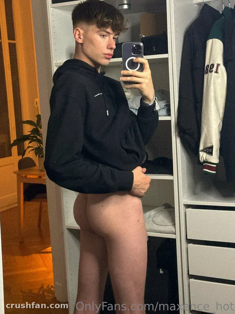 Maxence in a black hoodie taking a mirror selfie beside a white wardrobe
