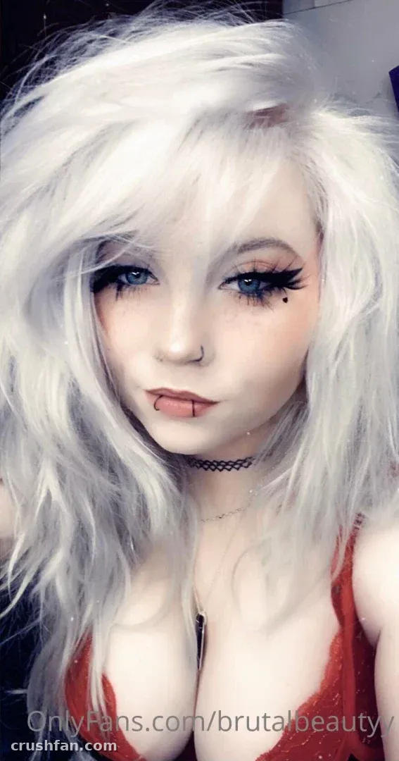 Selfie en gros plan de Brutalbeautyy avec des cheveux argentés, un eye-liner sombre et un haut rouge