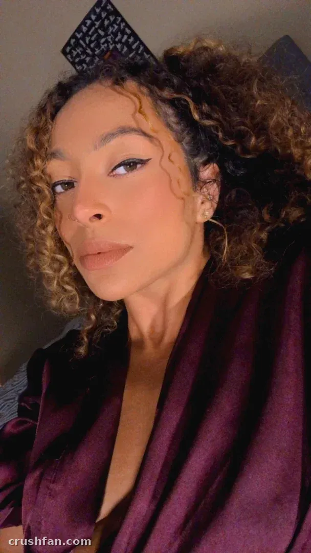 Leah in a plum satin robe with curly hair and a patterned hair accessory