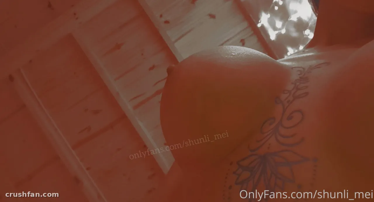 Nahaufnahme einer Schulter mit einem Blumentattoo in warmem orangem Licht vor Holzplanken