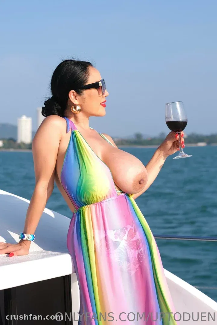 MYNAMEISDUANG en robe dos nu arc-en-ciel tenant du vin rouge sur le pont d'un bateau