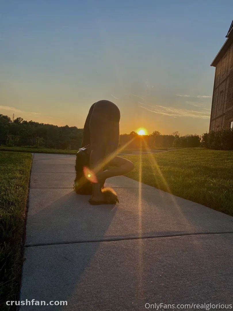 Glorious agachada em um caminho de concreto ao pôr do sol com um brilhante reflexo de sol atrás dela