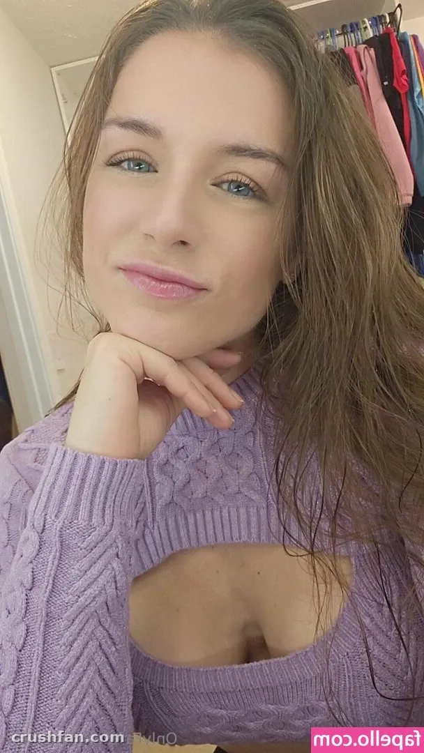 Kay Eufy in a lilac cable-knit top resting her chin on her hand indoors