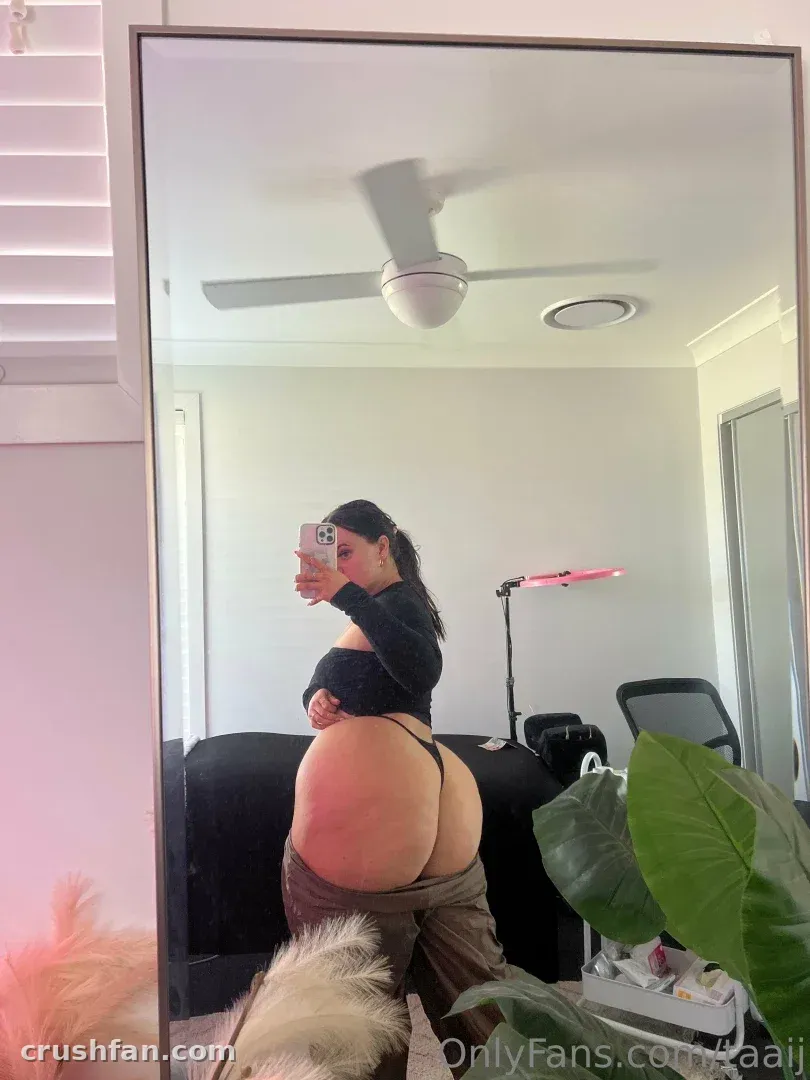 Creator TAAIJ takes a mirror selfie in a bright room with a ceiling fan and houseplant