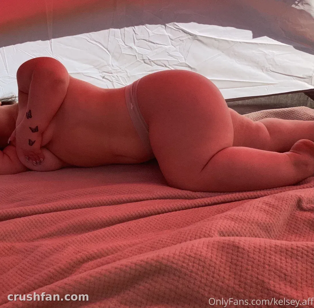 Kelsey Lawrence lying on a red blanket with white bedding behind her