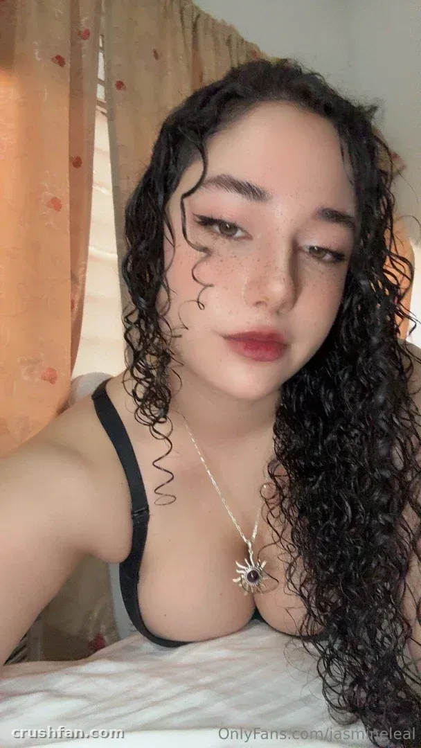 Jasmine Leal taking a close indoor selfie with curly hair and a pendant necklace