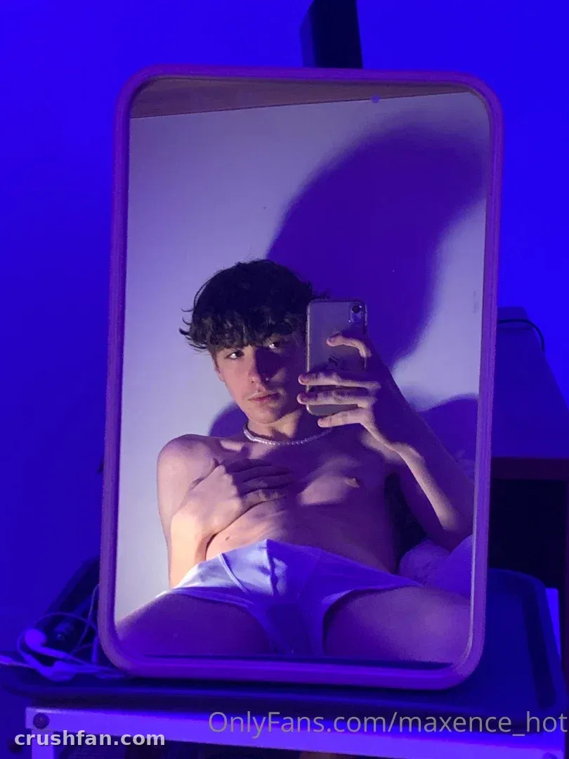 Maxence taking a mirror selfie under blue lighting, wearing a pearl necklace.