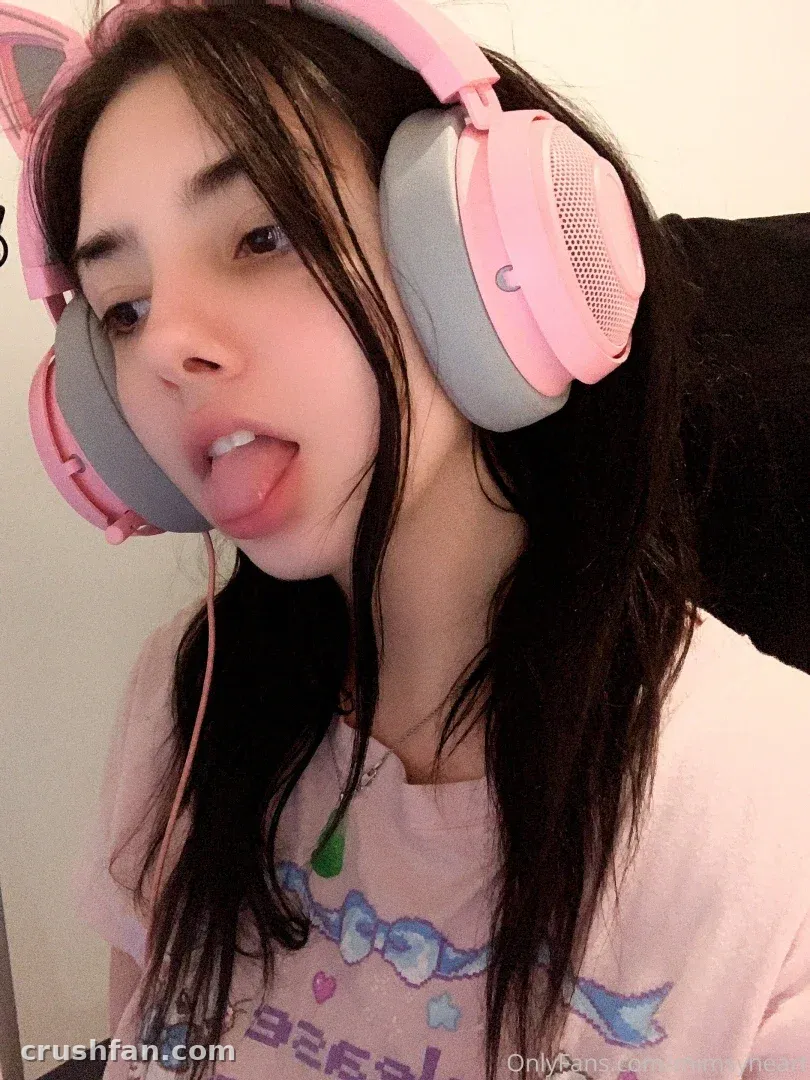 Amber in pink cat-ear headphones and a pink graphic top indoors