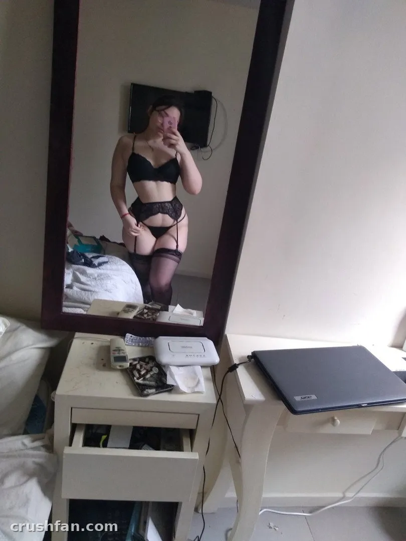 CandyRobbs tirando uma selfie no espelho em lingerie preta dentro de um quarto