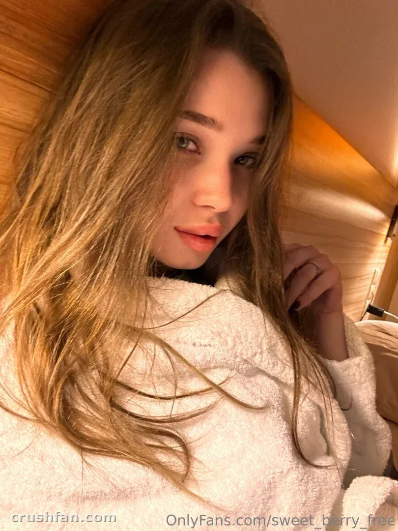 Sweet Berry in a white robe with long hair, warm indoor lighting