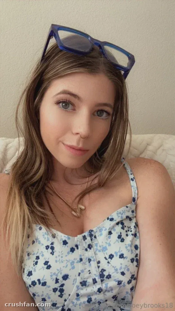 Zoey Brooks wearing a blue floral top with sunglasses resting on her head
