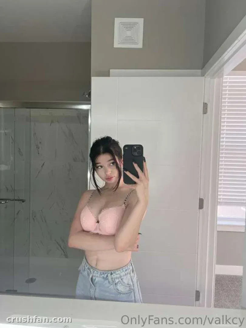 Ren ♡ poses for a mirror selfie in a pink top and light jeans in a bright bathroom.