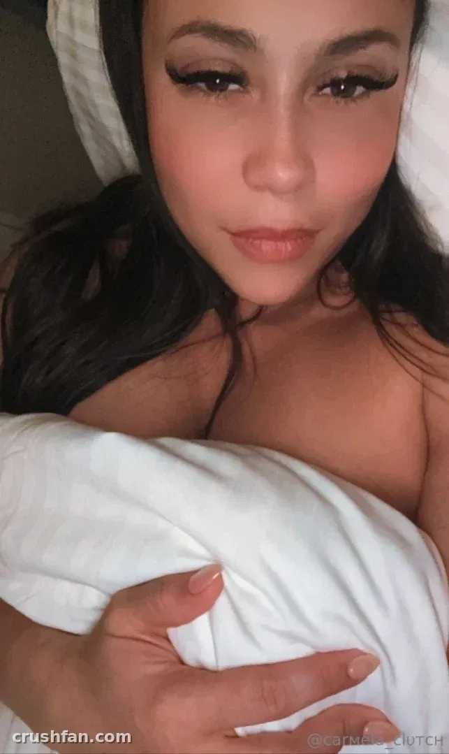 Close-up portrait of Carmela Clutch resting against white pillows and bedding