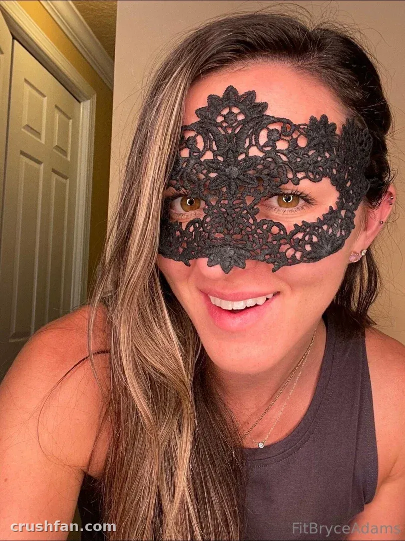 Bryce Adams in einer schwarzen Spitzen-Masquerade-Maske, lächelnd in einem Nahaufnahme-Innen-Selfie.