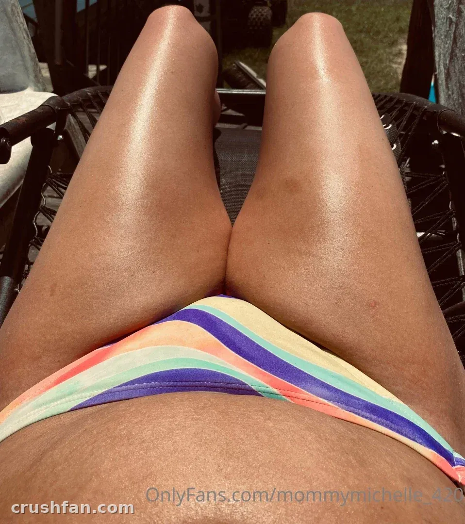 Close low-angle view of a striped bikini bottom and legs resting on a black mesh lounge chair outdoors.