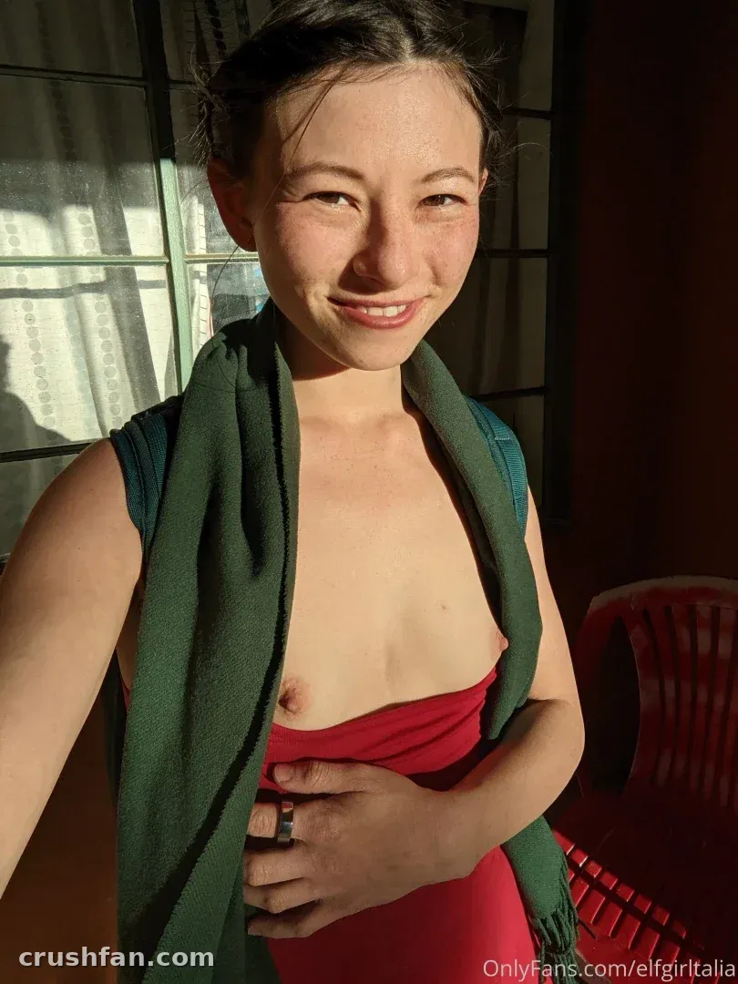 Smiling woman indoors with a green scarf over her shoulders in warm window light