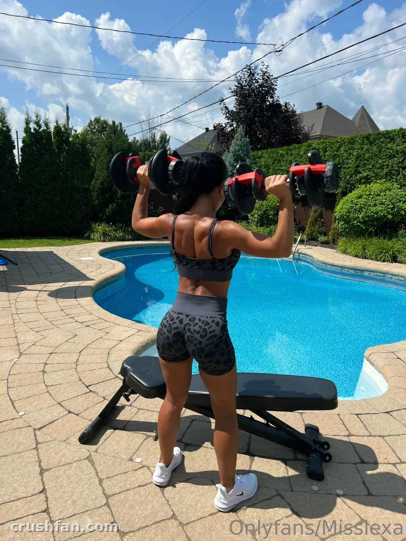 Miss Lexa lifting dumbbells on a patio beside a backyard pool on a sunny day