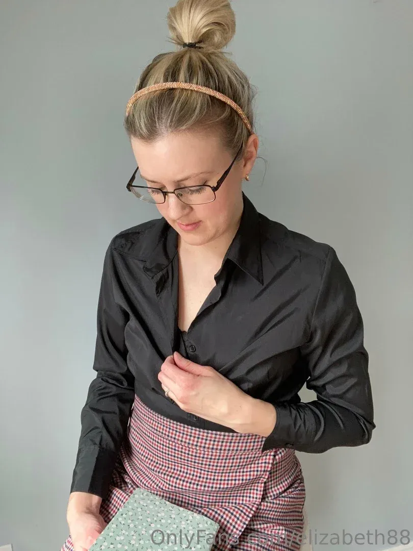Liz Parker in a black shirt and checked apron against a grey wall