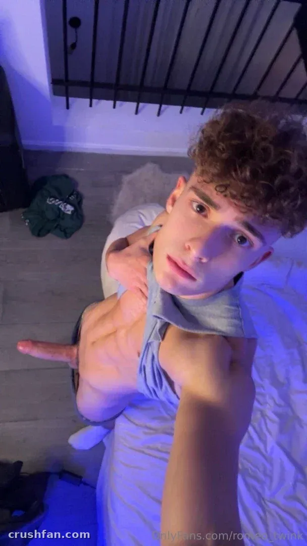 Romeo in a grey top taking a selfie under blue indoor lighting