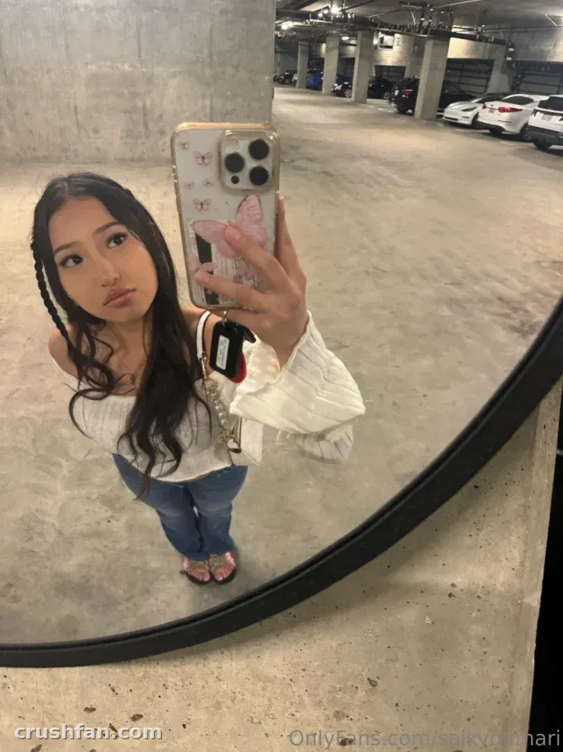 Maria en haut blanc et jean prenant un selfie dans le miroir dans un parking