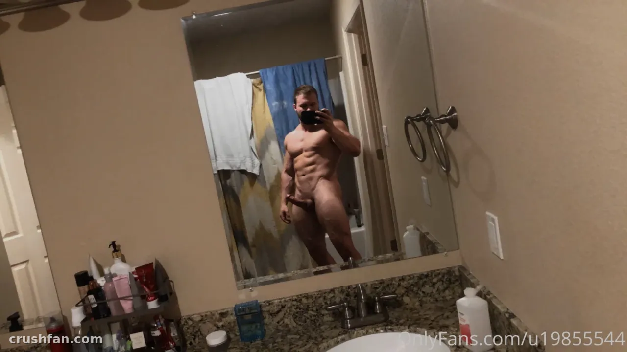 El reflejo del creador en un espejo de baño mientras sostiene un teléfono para una selfie