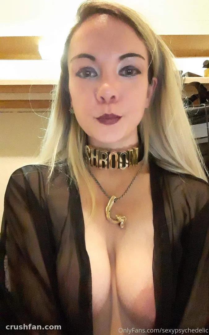 Teresa Mycelia in a sheer black robe with a gold choker and pendant indoors