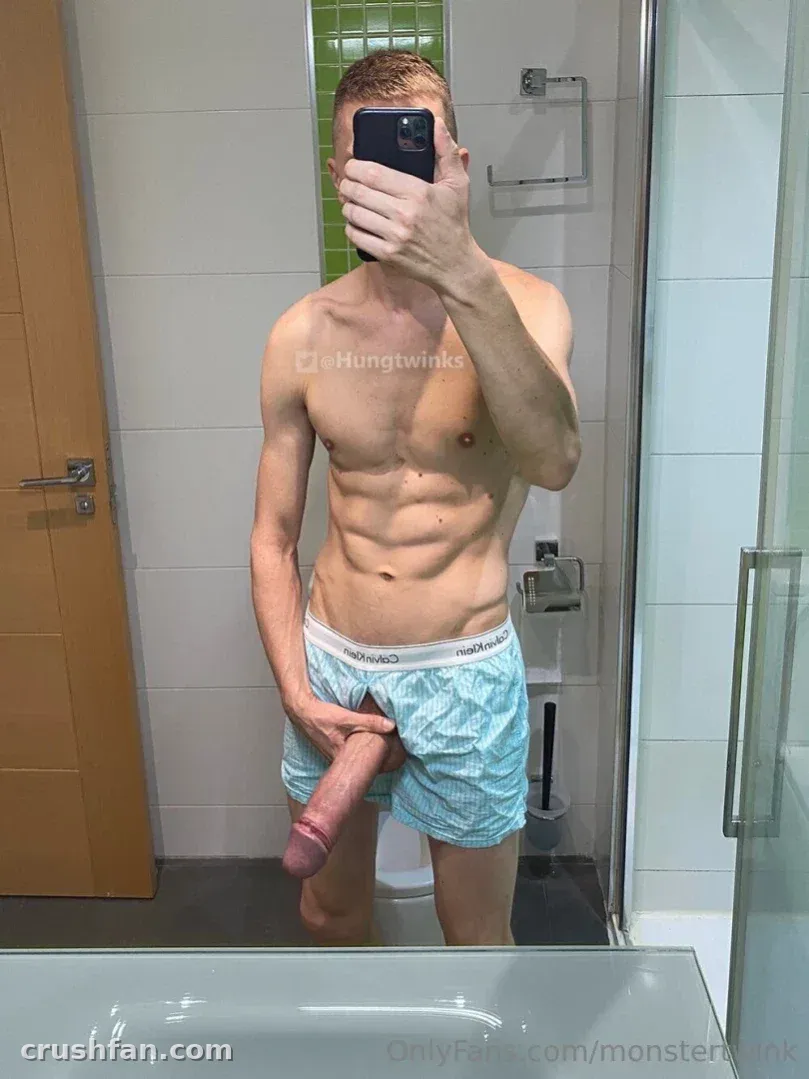 Monster Twink taking a mirror selfie in a tiled bathroom wearing light blue boxer briefs.