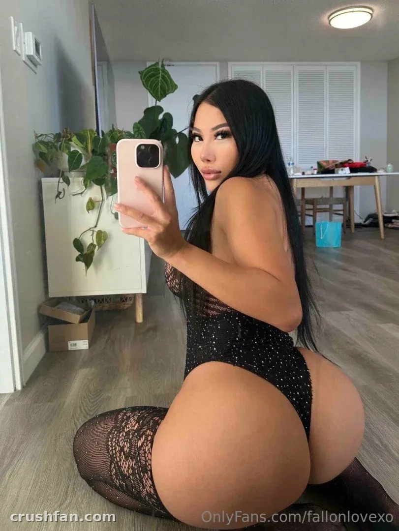 Fallon in a black sparkly bodysuit and lace stockings taking a mirror selfie indoors