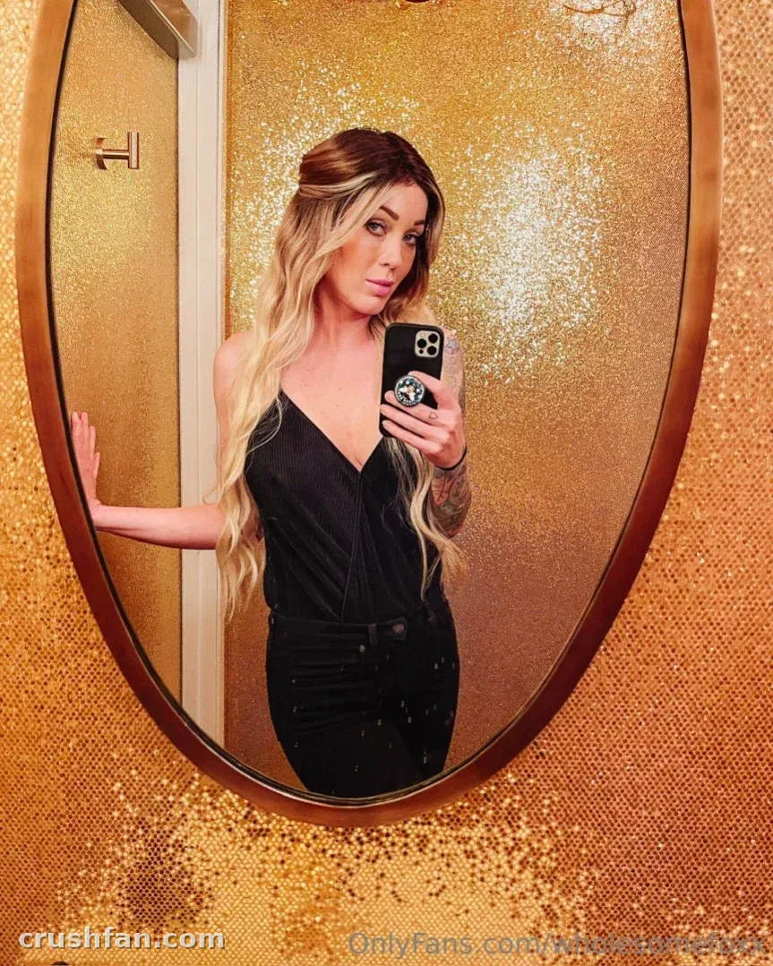 Créatrice en haut noir prenant un selfie miroir devant un mur de sequins dorés