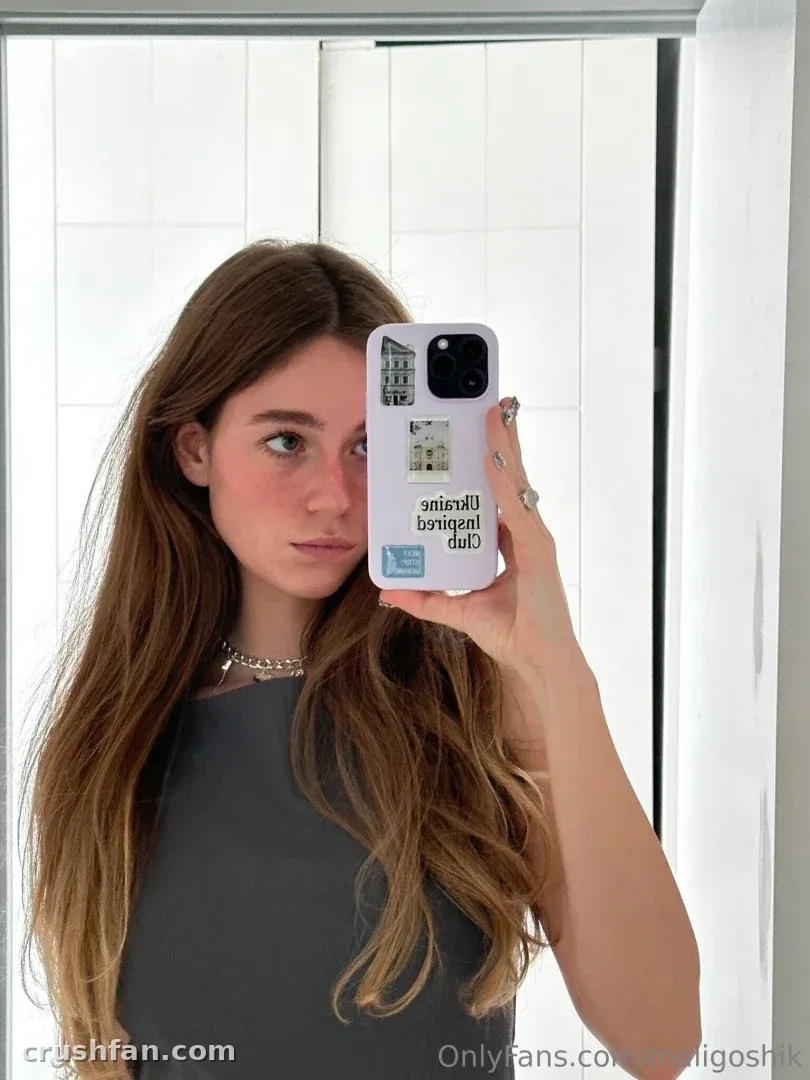 Anna in a grey top holding a printed phone case in a bright mirror selfie