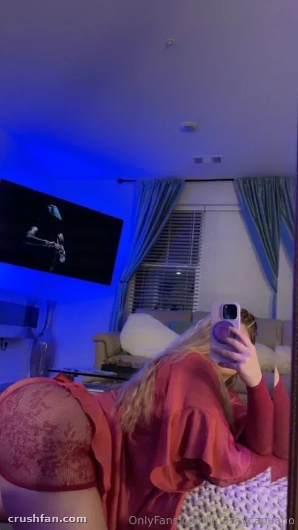 Lindsay Capuano tomándose una selfie de espejo en una sala de estar con luz azul