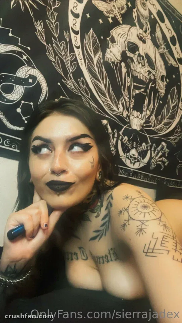 Sierra Jade takes a close-up selfie in front of a gothic skull tapestry.