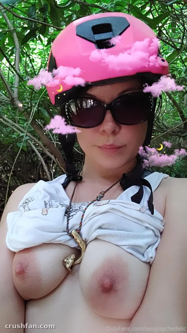 Creator in a pink helmet and sunglasses outdoors against green leaves