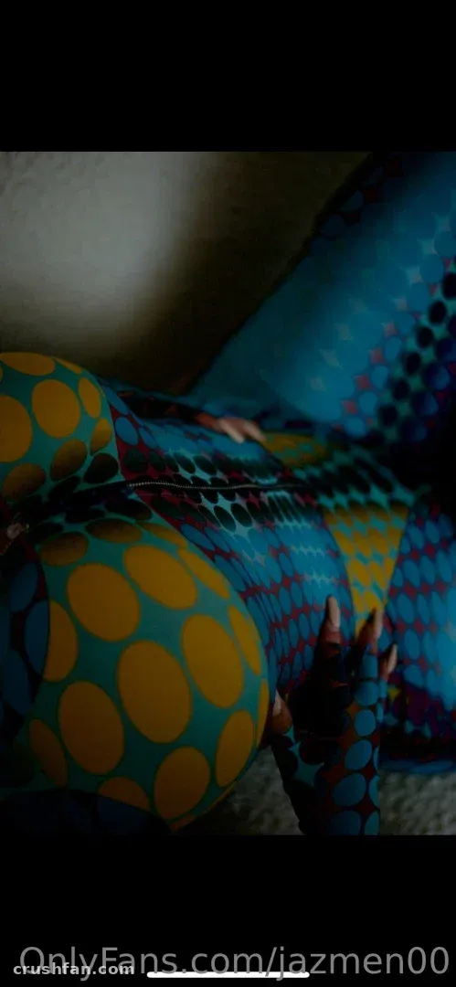 Jazmen Jafar vestindo um body estampado em azul e mostarda sob luz interna baixa.