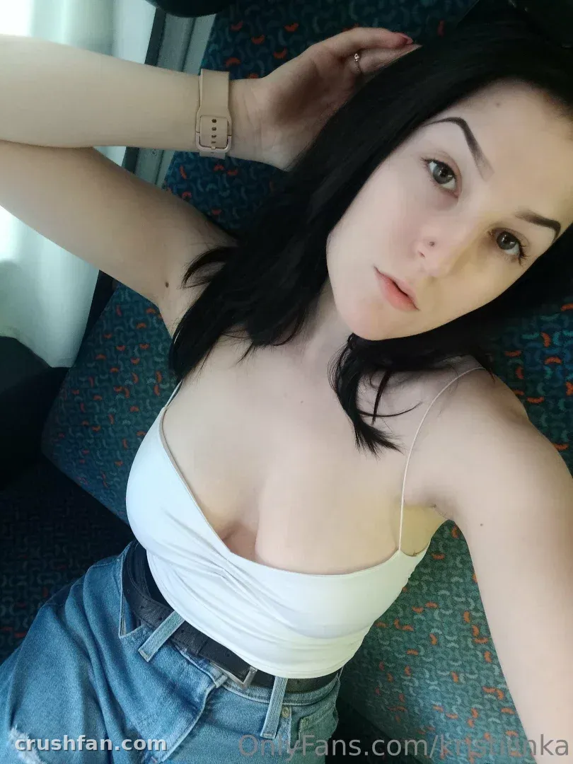 Kristiiina con un top blanco y shorts de mezclilla tomándose una selfie mientras está recostada en un asiento estampado.