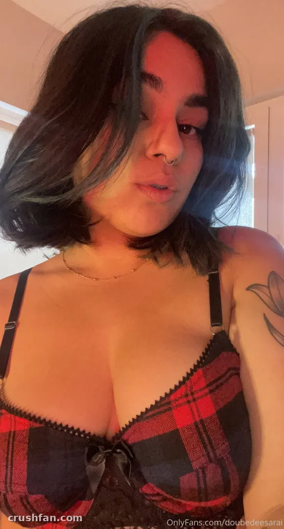 Selfie de cerca en interiores de Sara con un top de cuadros rojo y negro y un collar de cadena