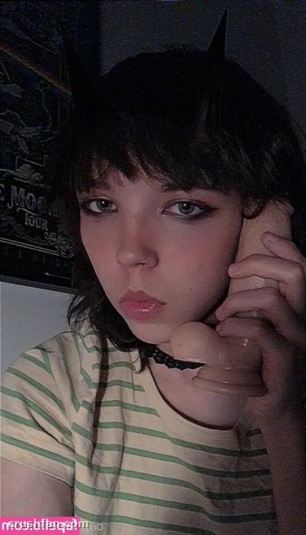 Close-up portrait of a woman in a striped shirt holding a phone to her ear in a dim room