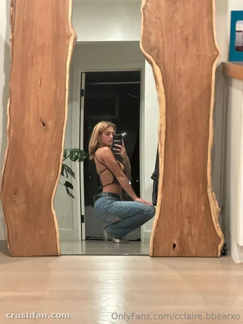 Claire Bear se agacha para una selfie en el espejo entre dos paneles altos de madera.