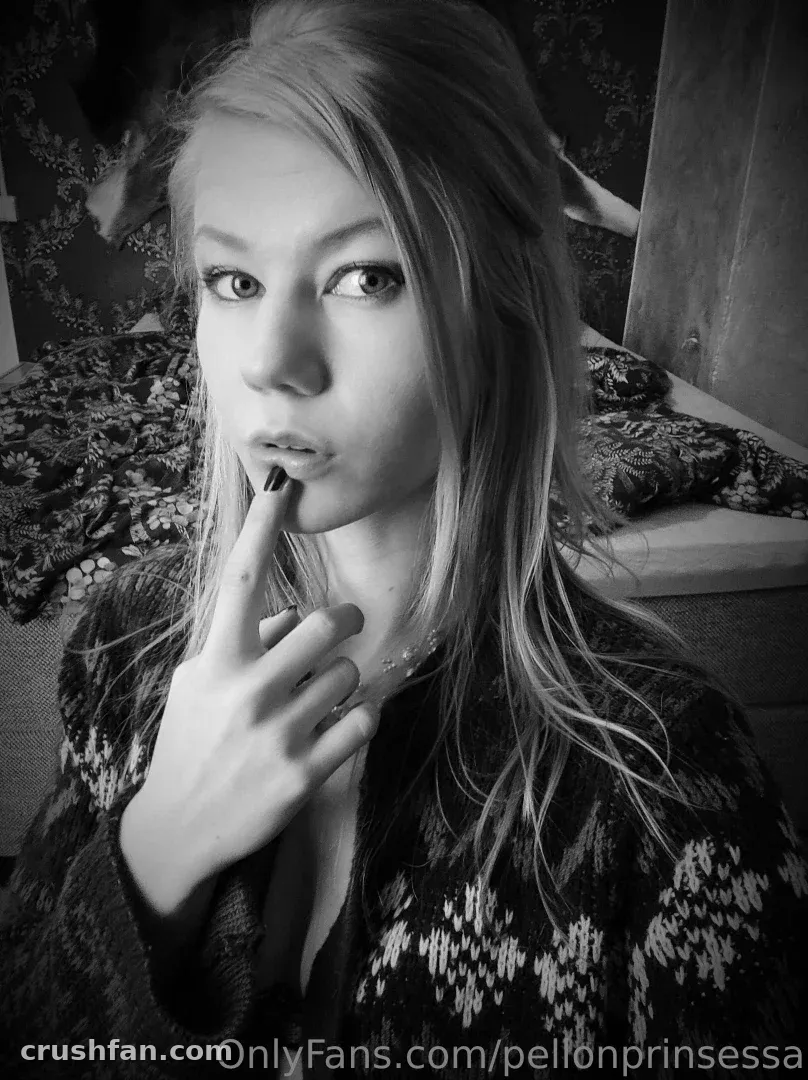 Black and white selfie of Marjatta with a finger to her lips, wearing a patterned cardigan.