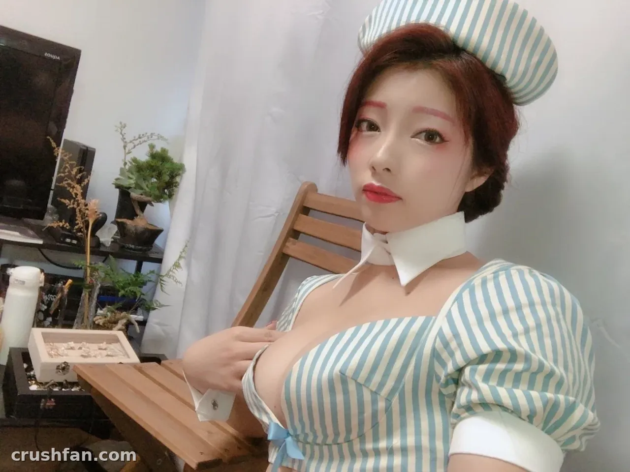 Tunamayo assise à l'intérieur dans un costume rayé bleu et blanc avec un chapeau haut et un col blanc.